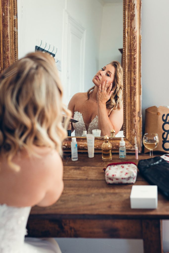 la mariée finalise son maquillage dans un joli miroir ancien