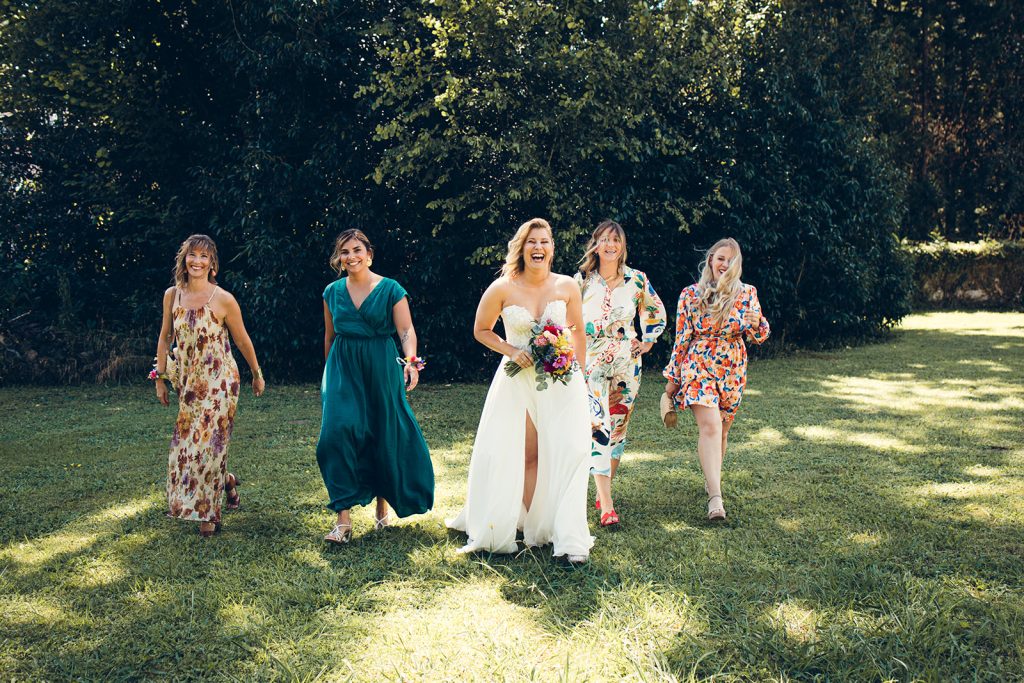 la mariée et ses témoins dans le jardin du domaine riant aux éclats dans une jolie lumière