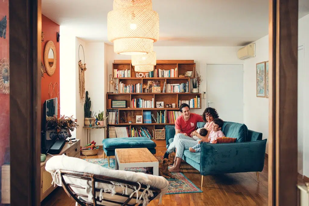 la famille est assise et complice dans leur salon magnifiquement décoré bohème vintage lors d'une séance naissance à domicile à nay
