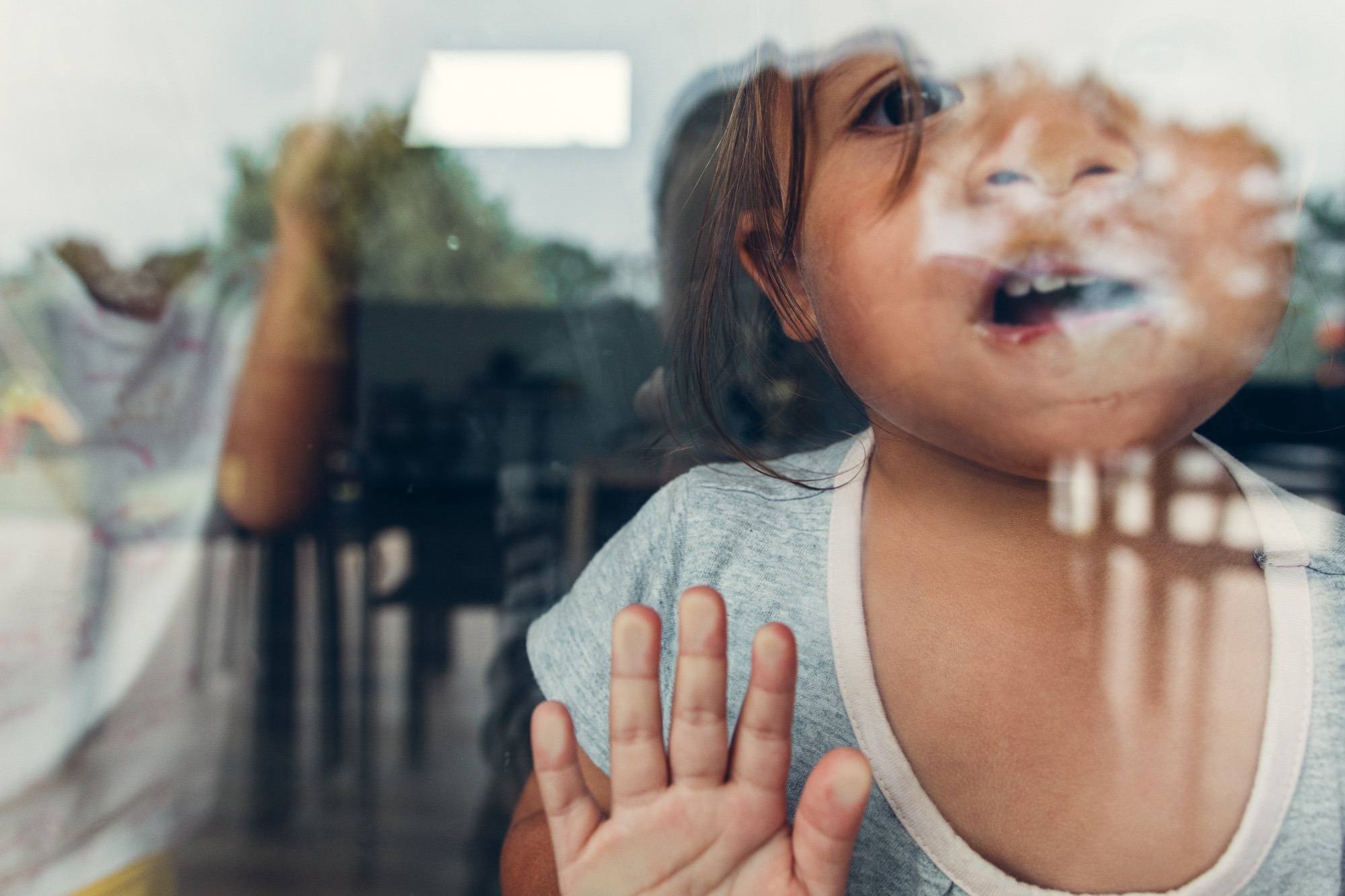 enfant qui fait un bisou sur la vitre lors d'une séance photo famille à domicile à pau