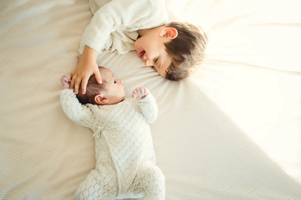 complicité d'un frère et d'une soeur sur le lit des parents à domicile lors d'une séance naissance à Pau