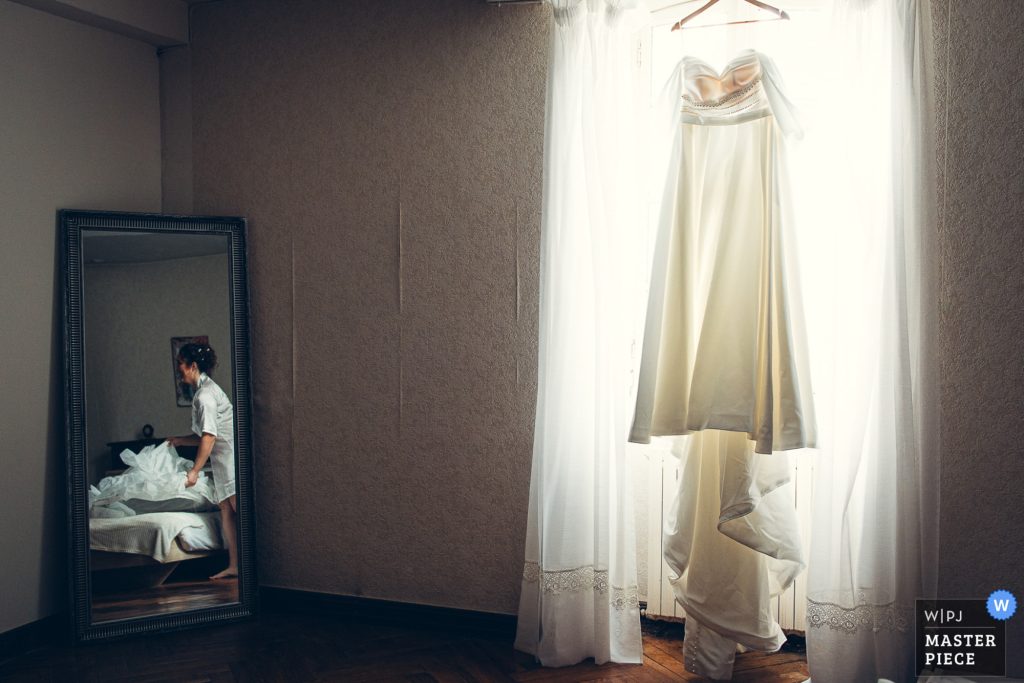 robe de la mariée mise en lumière suspendu pendant les préparatifs de la mariée au domaine bourdale dufau