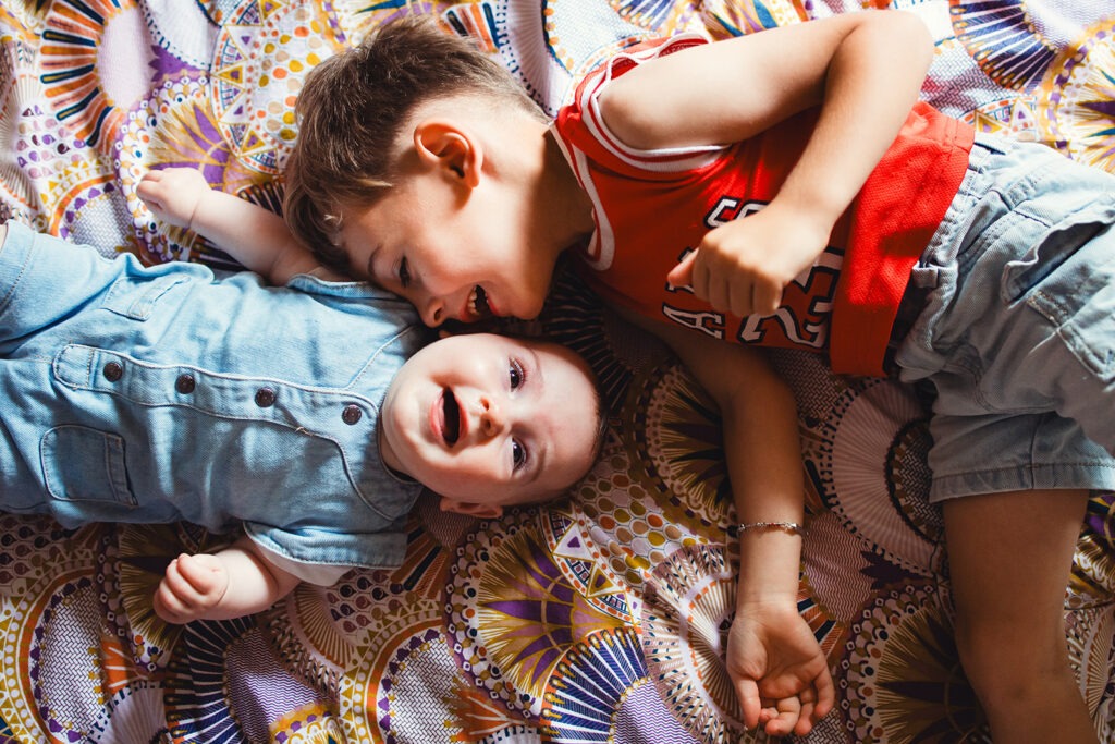 complicité entre frère et soeur sur le lit lors d'une séance photo naissance oloron sainte marie