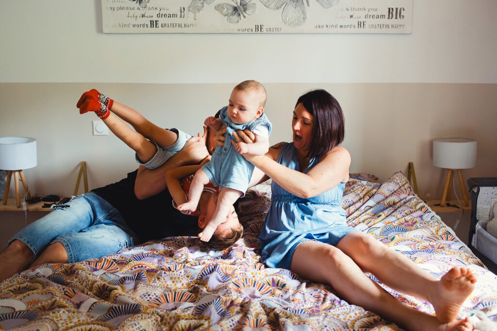 la famille joue sur le lit lors séance photo naissance oloron sainte marie