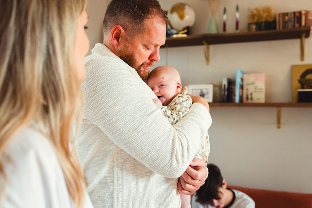 le bébé sourit à sa maman dans les bras de son papa séance naissance domicile soumoulou